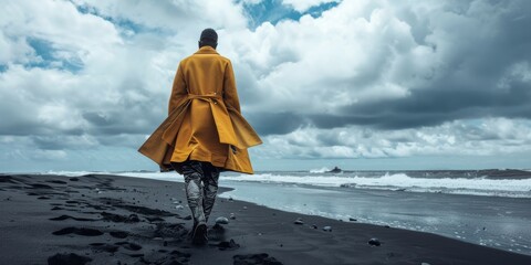 hombre con ropa amarilla paseando por una playa de arena negra, fotografía editorial minimalista...
