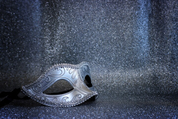 Photo of elegant Venetian mask over glitter silver background