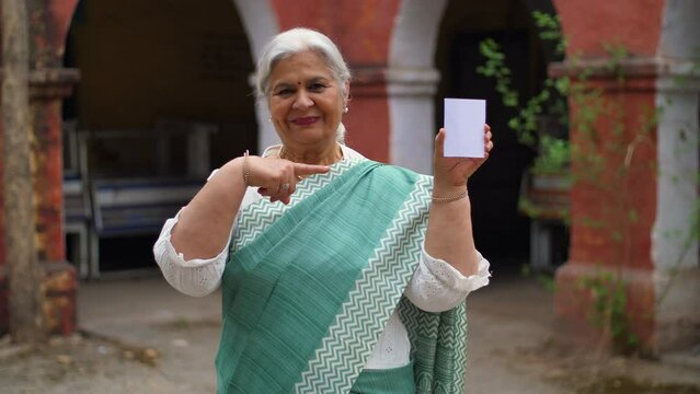 A grey-haired  aged Indian lady shows her voter identification card before elections. Old lady completing her responsibility of casting a vote during the elections - right to vote  senior citizen