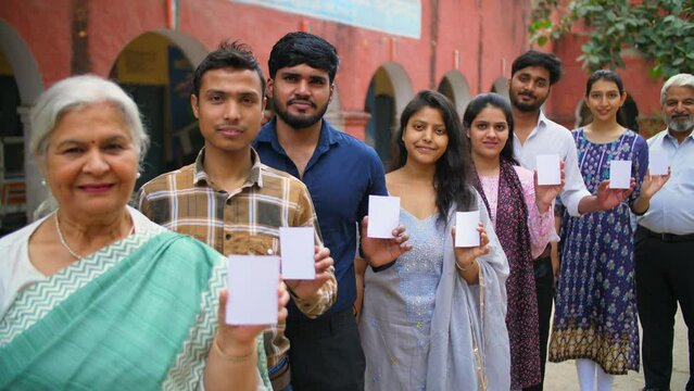 Responsible citizens of all age standing in a queue outside the polling booth to cast their vote - assembly elections . Active voters showing their voter identification card - evm  registered voter...