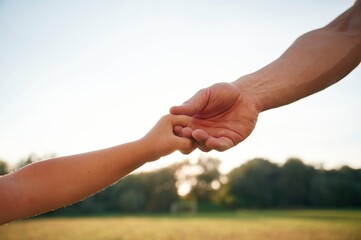 Close up view of dad and his little son hands that are holding each other