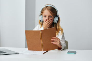 Smiling girl using laptop for elearning at home A cute, young schoolgirl sits at her desk in a...