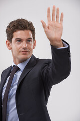 Businessman, palm and hand with touch for interaction, virtual display or connection on a gray studio background. Isolated young man, user or business employee showing gesture sign, symbol or wait