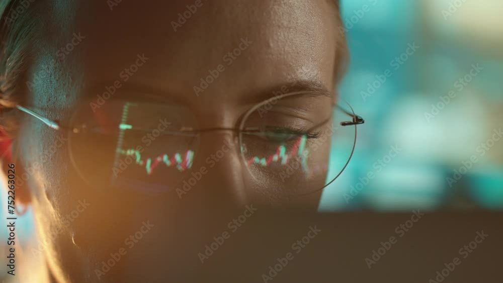 Poster trader wearing glasses is working on laptop computer. screen with stock market charts and bitcoin bt