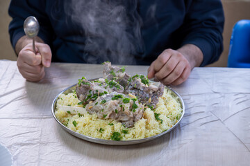 male hands with mansaf from a point of view while preparing his plate with meat,rice jameed ,nuts...