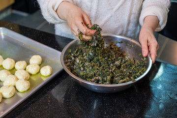 preparing arabic traditional pastries by female hands stuffing them with spinach and red chili