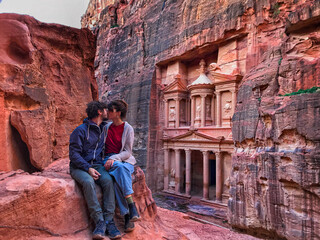couple kissing with the facade of Petra in the background looking at the lost city. Love in Petra. one of the new seven wonders of the world.