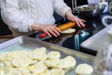 old woman hands using rolling pin to flatten the dough  on black marble  covered with oil