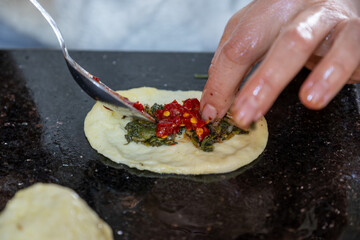 preparing arabic traditional pastries by female hands stuffing them with spinach and red chili