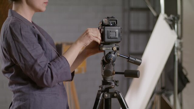 Work in a professional photo studio. Photographer on a photo shoot. Film camera and retro camera on a wooden tripod. Roll film back adapter dark slide shading sheet. Load the film into the cassette.