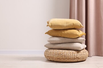 Soft pillows on wicker pouf in room, space for text