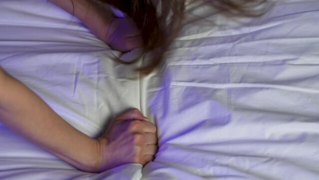 Passion woman squeezed the bed sheet with her hand