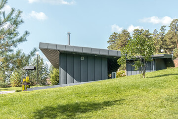 Modern guest house with standing seam facade panoramic glazing and large flat roof overhang in...