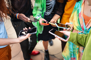 Group of modern diverse queer young people holding cell phones in their hands during music festival