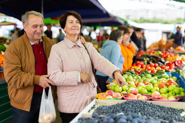 Elderly man and a woman buy berries at an open air market
