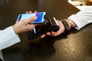 Young woman making payment via credit card at a machine in a cafe - obrazy, fototapety, plakaty