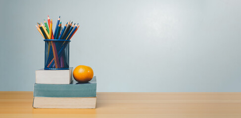 Stack of colorful textbooks and a glass of bright pencils on a white background, Concept of...