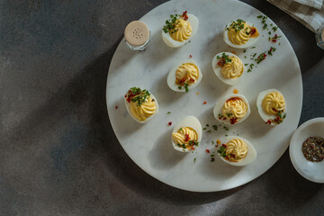 Deviled eggs with spicy oil on dark gray background with sunligh and harsh shadows, directly above - 752297070