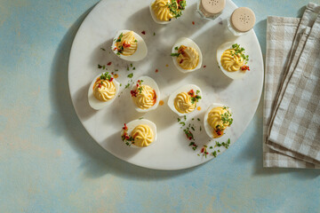 Deviled eggs with spicy oil on ligh blue background with sunligh and harsh shadows, directly above - 752297078