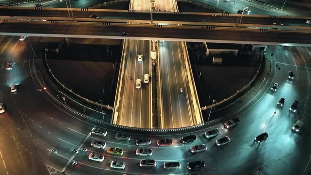 Financial technology, energy power, beautiful top view time-lapse of car traffic at roundabout lane and buildings. drone aerial expressway. Urban cityscape concept or abstract of advanced innovation.