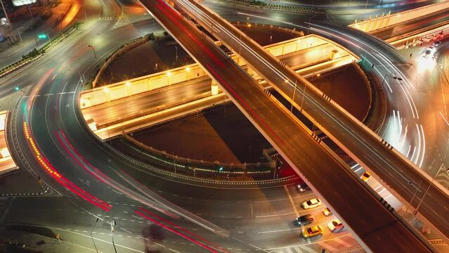 Financial technology, energy power, beautiful top view time-lapse of car traffic at roundabout lane and buildings. drone aerial expressway. Urban cityscape concept or abstract of advanced innovation.