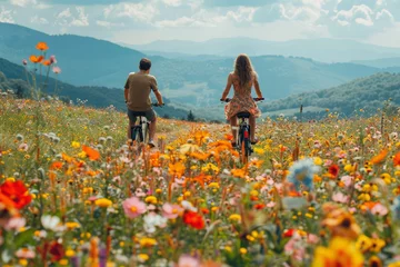 Foto auf Glas A man and a woman joyfully ride their bikes through a vibrant field of colorful flowers on a sunny day © nnattalli