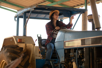 Fototapeta na wymiar Proud female farmer with a straw hat drives a tractor, a blend of traditional and modern farming.