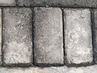 Close-up of a weathered red brick wall with peeling paint, revealing the aged texture and imperfections of the bricks.