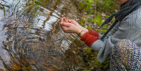 Open hands holding water in the forest