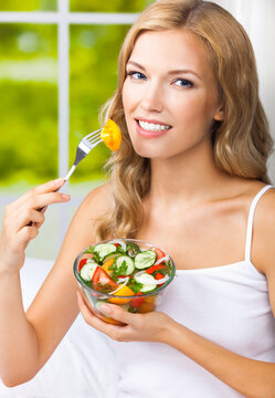 Portrait image - blond blonde woman holding glass bowl with vegetable salad home house, indoors. Healthy eating, vegetarian, keto ketogenic diet concept.