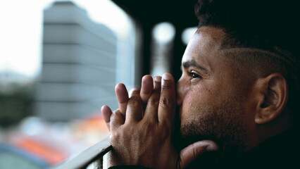 One depressed young man struggling with life's challenges gazing at view from balcony, profile...