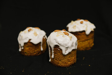 Easter cakes with white icing and almond nuts on a black background. 