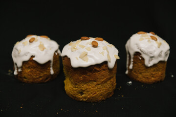 Easter cakes with white icing and almond nuts on a black background. 