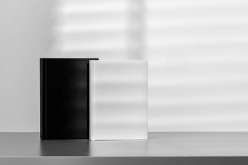 Black and white notepads standing on gray desk against gray background with shadow