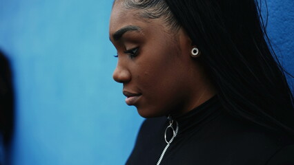 One pensive worried black adolescent girl with thoughtful expression, close-up face tracking shot...