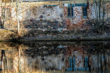 Reflection in the water of a brick building on a small river
