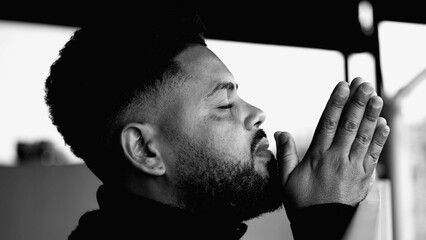 One Spiritual young black man in deep PRAYER contemplating GOD and eternity with hands clenched...