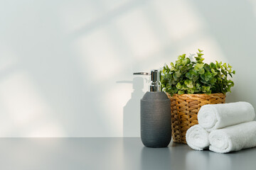 Soap dispenser and spa towels on white background in shadow