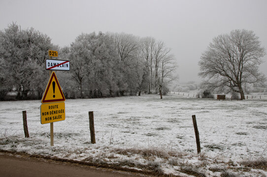 Frosty Morning in the French village of Damblain  With Snow-Covered Trees and "Unsalted, unplowed road" Warning Sign