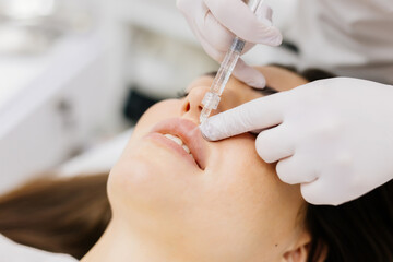 The procedure for lip augmentation and correction in a cosmetology salon. The specialist gives an...