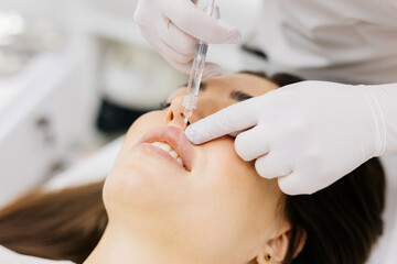 The procedure for lip augmentation and correction in a cosmetology salon. The specialist gives an...
