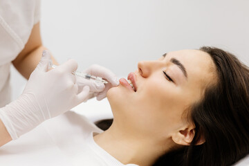 Injection lip augmentation. Close-up of beautician's hands doing cosmetic procedures for sexy...