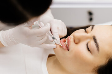 Injection lip augmentation. Close-up of beautician's hands doing cosmetic procedures for sexy...