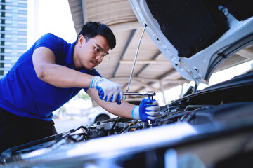  automobile car concept. Asian auto mechanic in blue uniform works on car engine Repair and customer service Working on engines in the garage. 