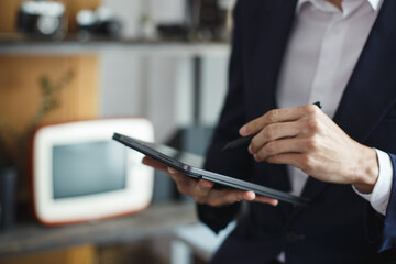 Closeup of digital tablet, successful businessman pointing typing touchpad working at office.