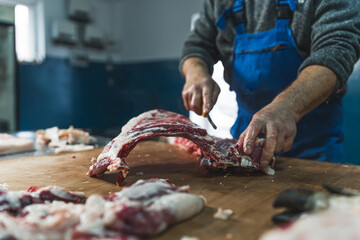 butcher cut raw meat of a pig with a knife at table in the slaughterhouse. High quality photo