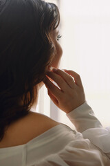 Rear view of brunette bride looking at the window. Close up photo. Copy space for text