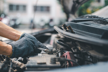 Skilled auto mechanic in gloves changing an expired car battery, focused on engine maintenance...