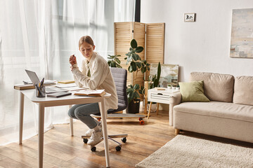 focused teenage girl using her laptop while sitting around books, online education concept