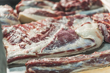 Big pork slices are on the table, adding salt and preparing them for sale. High quality photo